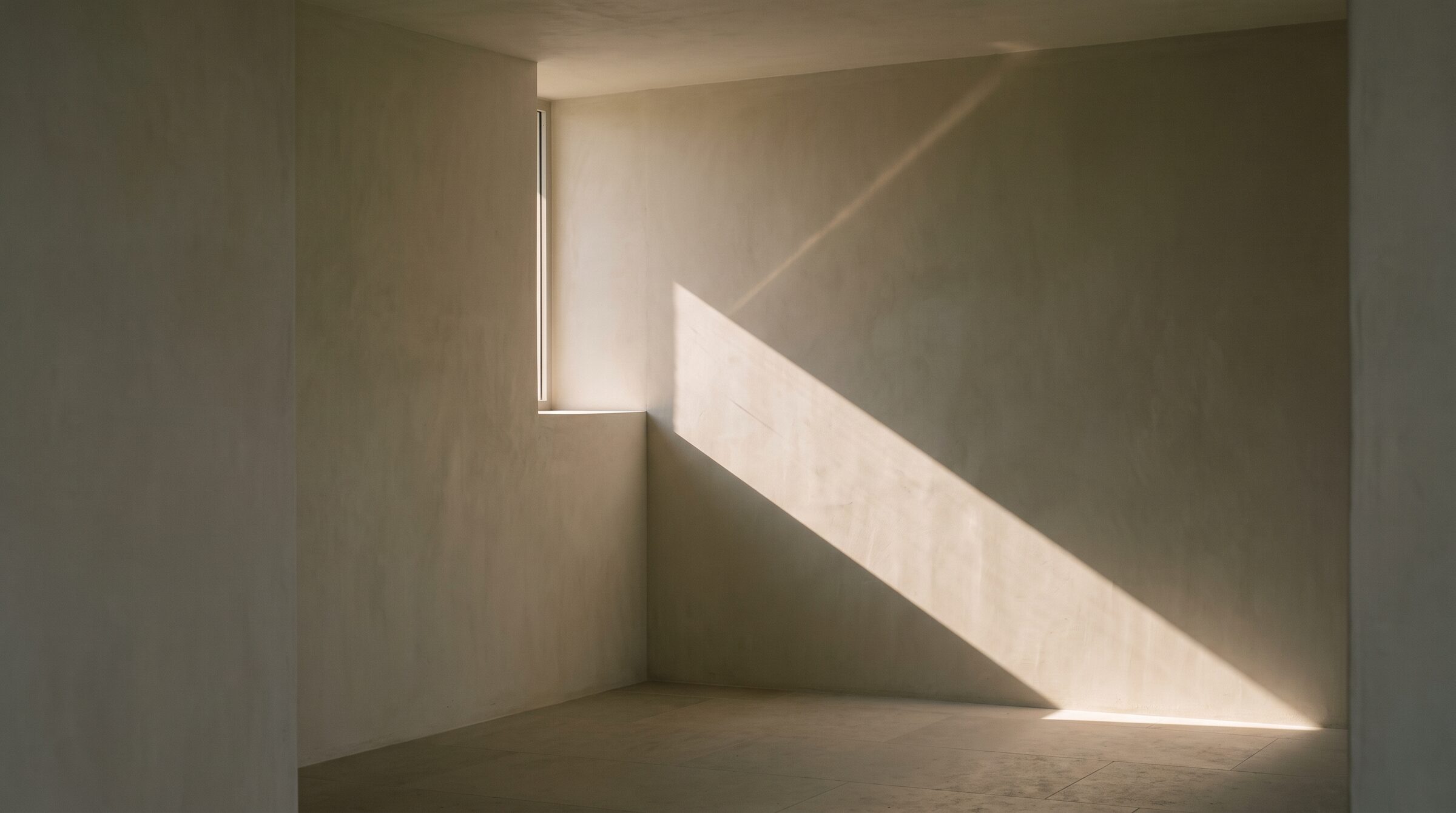 Ein Streifen Sonnenlicht aus einem schmalen Fenster auf einer Kalkputzwand